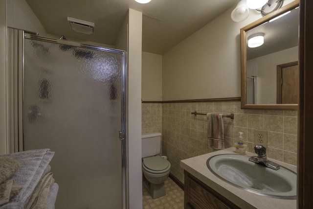 full bathroom with tile walls, wainscoting, a stall shower, vanity, and toilet