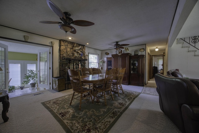 dining room with a ceiling fan, a textured ceiling, visible vents, light colored carpet, and stairway