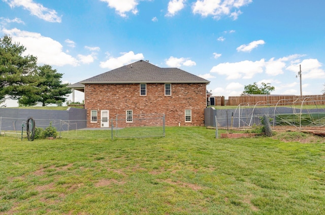 back of house with a yard, brick siding, and a fenced backyard