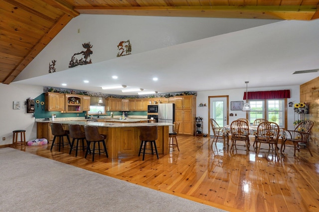kitchen featuring light wood-type flooring, open shelves, a breakfast bar area, and beam ceiling