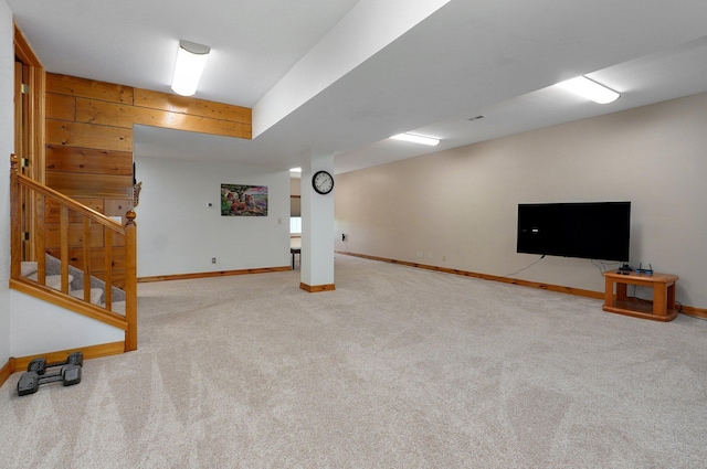 finished below grade area featuring baseboards, carpet, stairs, and wood walls