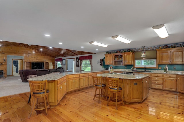 kitchen with plenty of natural light, a breakfast bar area, a large island, a sink, and light wood-style flooring