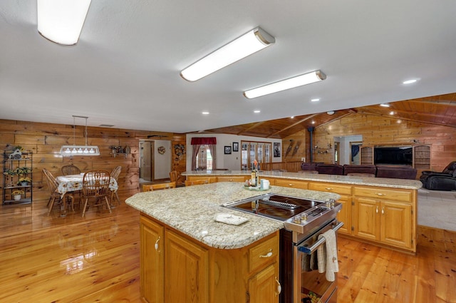 kitchen featuring lofted ceiling, light wood finished floors, wooden walls, stainless steel range with electric cooktop, and a kitchen island