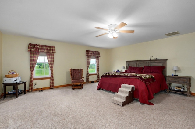 carpeted bedroom featuring baseboards, multiple windows, a ceiling fan, and visible vents