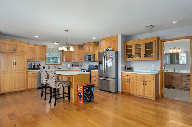 kitchen with light wood-style floors, stainless steel appliances, a kitchen bar, and a chandelier