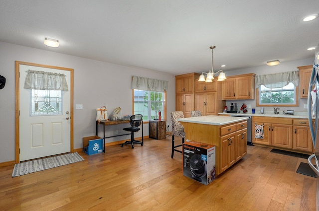 kitchen with a center island, dishwasher, light countertops, light wood finished floors, and a notable chandelier