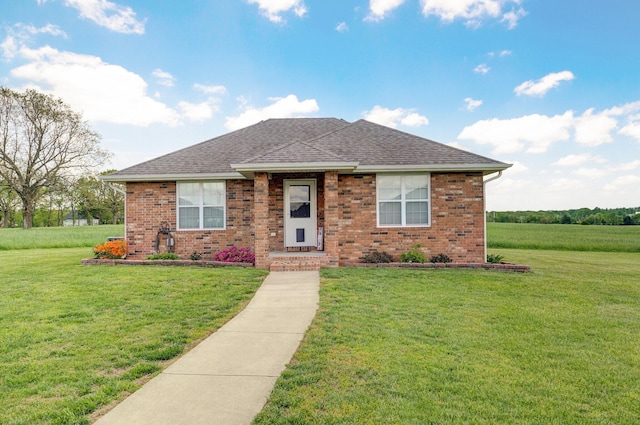 view of front of property featuring a shingled roof, brick siding, and a front lawn