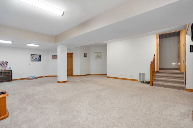 finished below grade area featuring carpet floors, baseboards, stairs, and visible vents