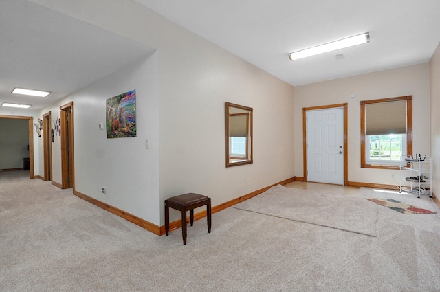 entryway with baseboards and light carpet