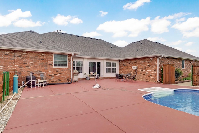 rear view of property with brick siding, a fenced in pool, a shingled roof, and a patio