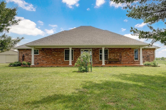 rear view of property featuring a lawn, brick siding, and a shingled roof