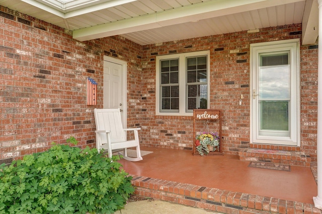 property entrance with covered porch and brick siding
