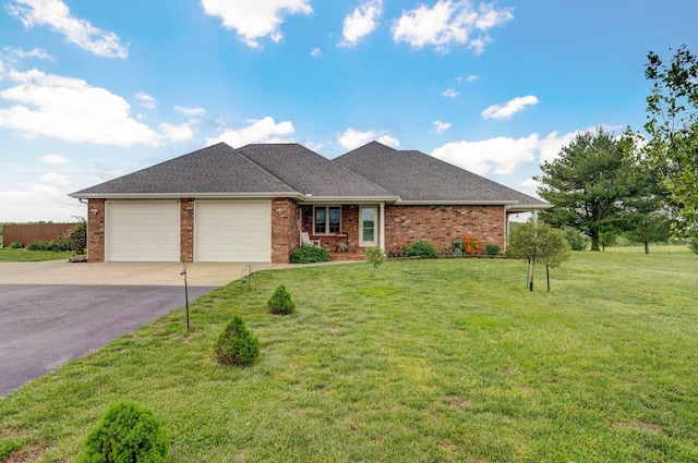 ranch-style home with an attached garage, a front yard, brick siding, and aphalt driveway