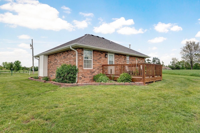 back of property with a yard, a deck, brick siding, and a shingled roof