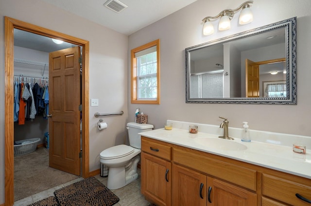 bathroom with a shower with door, toilet, visible vents, vanity, and a walk in closet