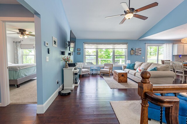 living room with a ceiling fan, healthy amount of natural light, dark wood finished floors, and vaulted ceiling