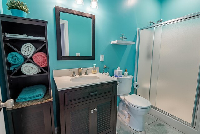 bathroom with a shower stall, vanity, and toilet