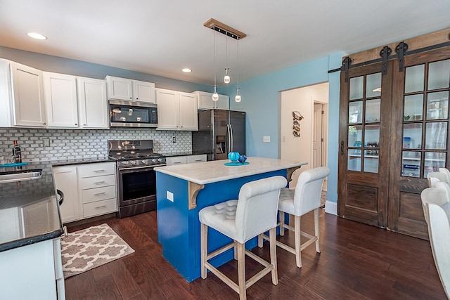 kitchen with stainless steel appliances, decorative backsplash, white cabinets, a kitchen island, and a kitchen breakfast bar