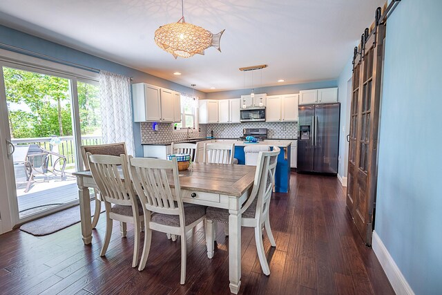 dining space featuring a barn door, plenty of natural light, dark wood-style floors, baseboards, and recessed lighting