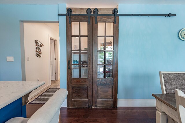 dining area view of baseboards, wood finished floors, and a barn door