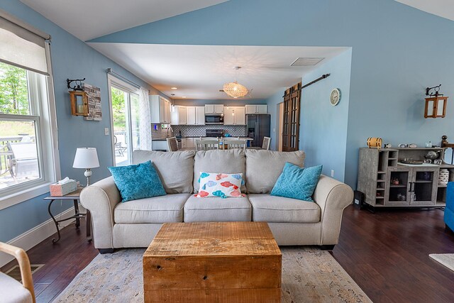 living room featuring wood finished floors, lofted ceiling, and a barn door