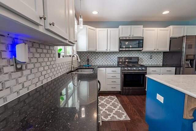 kitchen featuring stainless steel appliances, a sink, dark stone countertops, white cabinets, and recessed lighting