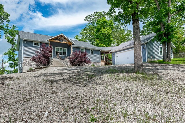 ranch-style home with an attached garage, driveway, stone siding, and covered porch