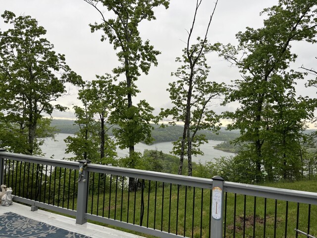 deck with a water view and a lawn