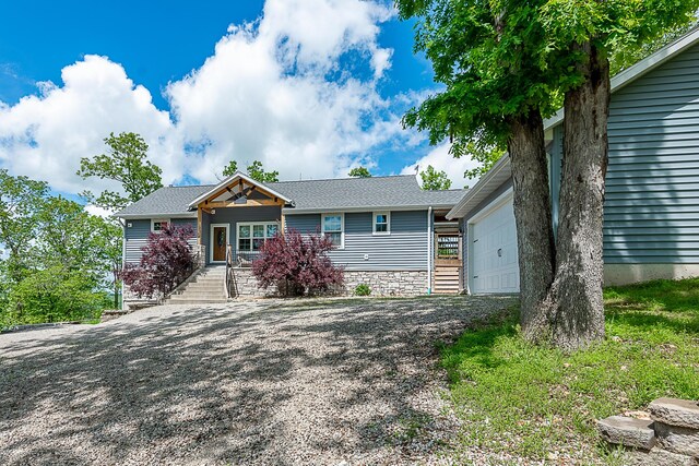ranch-style house with a garage, stone siding, a porch, and driveway