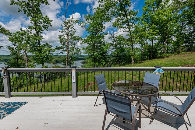 wooden deck with a water view and outdoor dining space