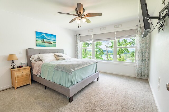bedroom with light colored carpet, baseboards, and ceiling fan