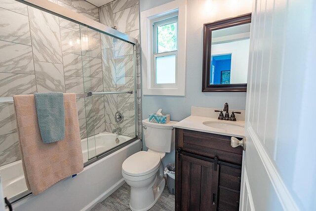 full bathroom featuring combined bath / shower with glass door, vanity, and toilet