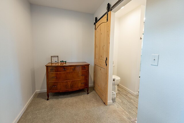 corridor featuring a barn door, baseboards, and light carpet