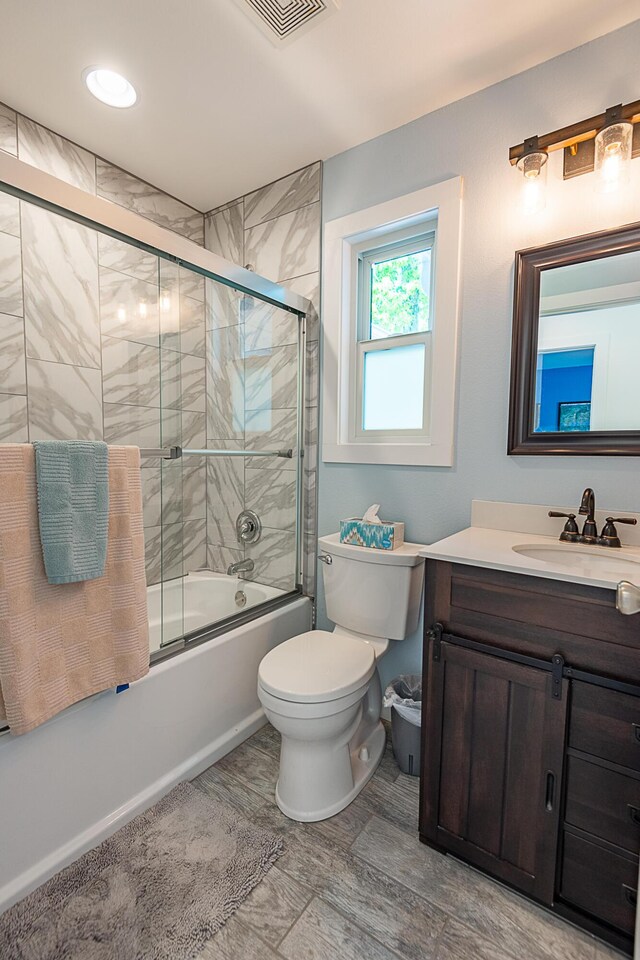 full bathroom featuring bath / shower combo with glass door, vanity, toilet, and baseboards