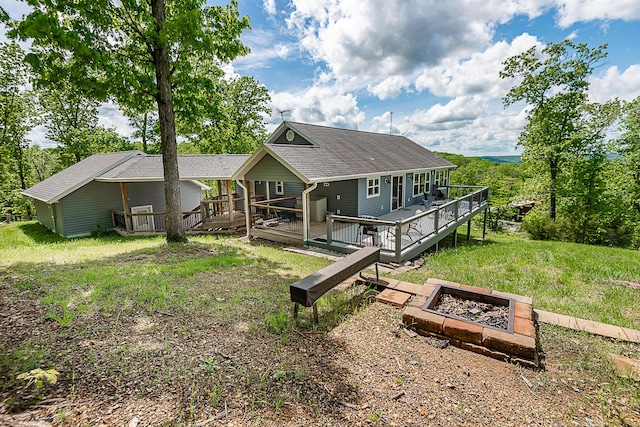 rear view of house with an outdoor fire pit, a wooden deck, and roof with shingles