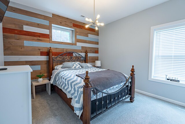carpeted bedroom with wood walls, a chandelier, and baseboards