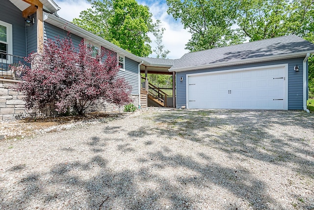 view of front of home with gravel driveway, an attached garage, and stairway
