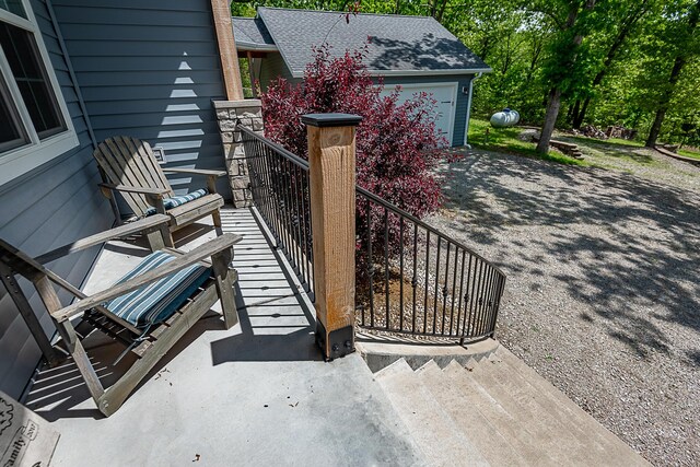 view of patio / terrace featuring a garage, driveway, and stairs