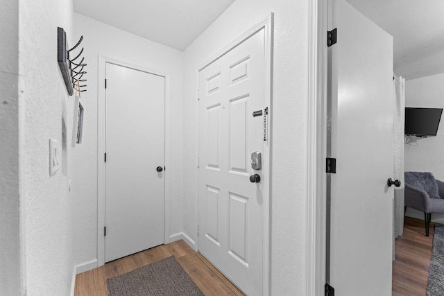 doorway featuring baseboards and wood finished floors
