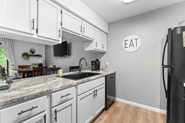 kitchen featuring freestanding refrigerator, light wood-type flooring, white cabinetry, a sink, and dishwasher