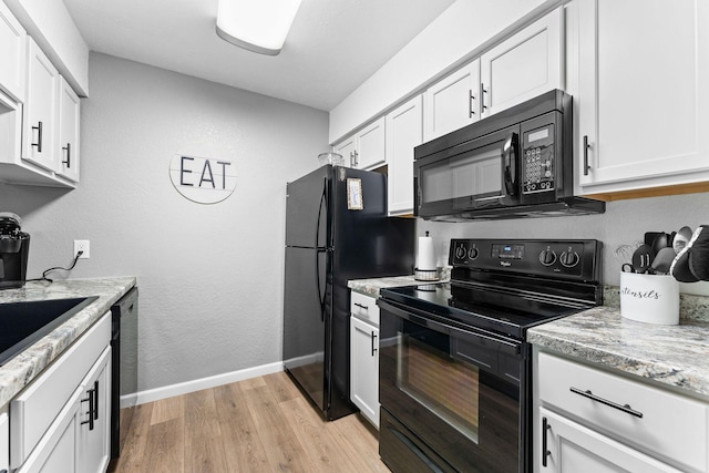 kitchen featuring light stone countertops, baseboards, white cabinetry, light wood-style flooring, and black appliances
