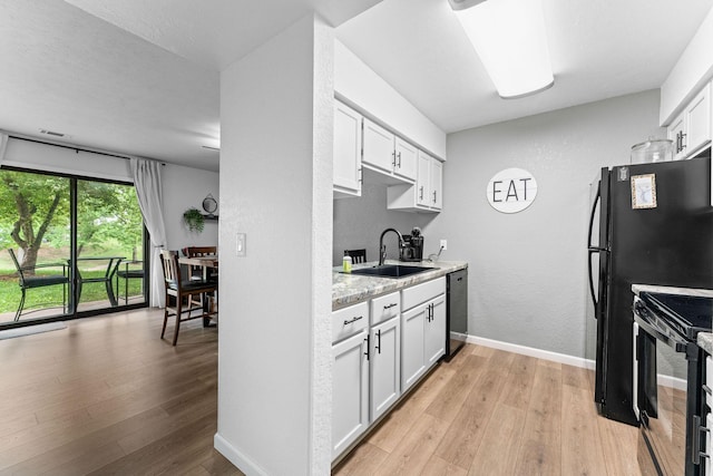 kitchen featuring a sink, light wood finished floors, black appliances, and white cabinetry