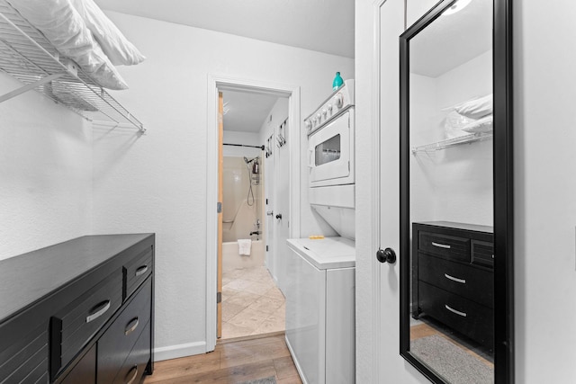 laundry area with light wood-type flooring, laundry area, and stacked washer and dryer