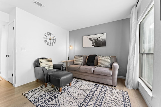 living area featuring baseboards, light wood-style flooring, and visible vents