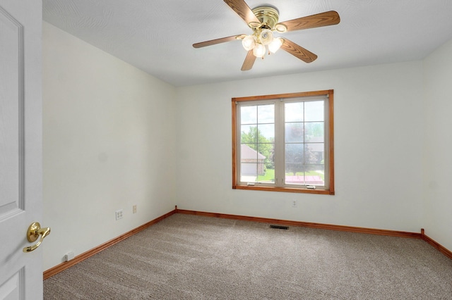 empty room with visible vents, carpet flooring, baseboards, and ceiling fan