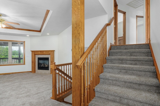 staircase featuring ceiling fan, a tiled fireplace, baseboards, carpet flooring, and recessed lighting