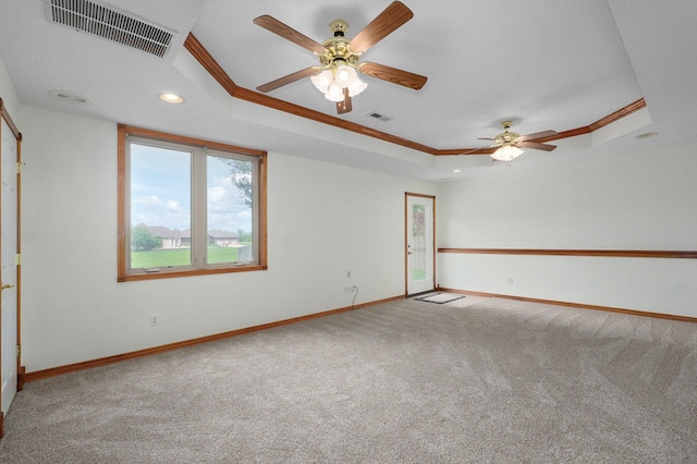 empty room featuring crown molding, a raised ceiling, carpet flooring, and visible vents