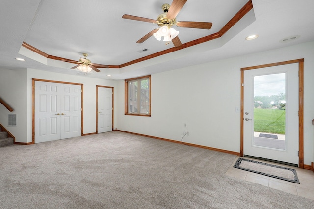 carpeted entryway with a raised ceiling, a wealth of natural light, and visible vents