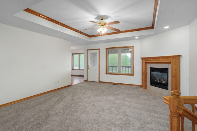 unfurnished living room featuring a ceiling fan, baseboards, carpet, and a tray ceiling
