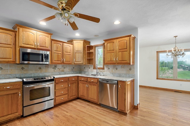 kitchen with a sink, appliances with stainless steel finishes, light wood finished floors, and light countertops